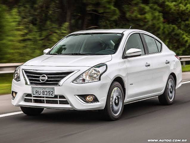 Sedã Nissan Versa branco em movimento em estrada com vegetação ao fundo